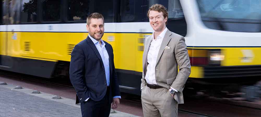 Attorneys Aaron Burke and Rob Bogdanowicz standing in front of a speeding train.